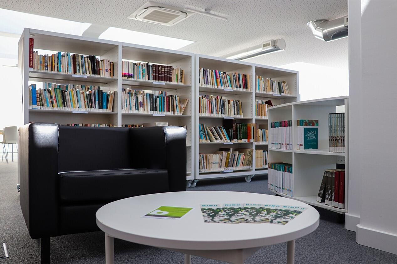 Zona de leitura da Biblioteca Municipal de Peniche, com cadeirão, mesa baixa e estantes Culturalis